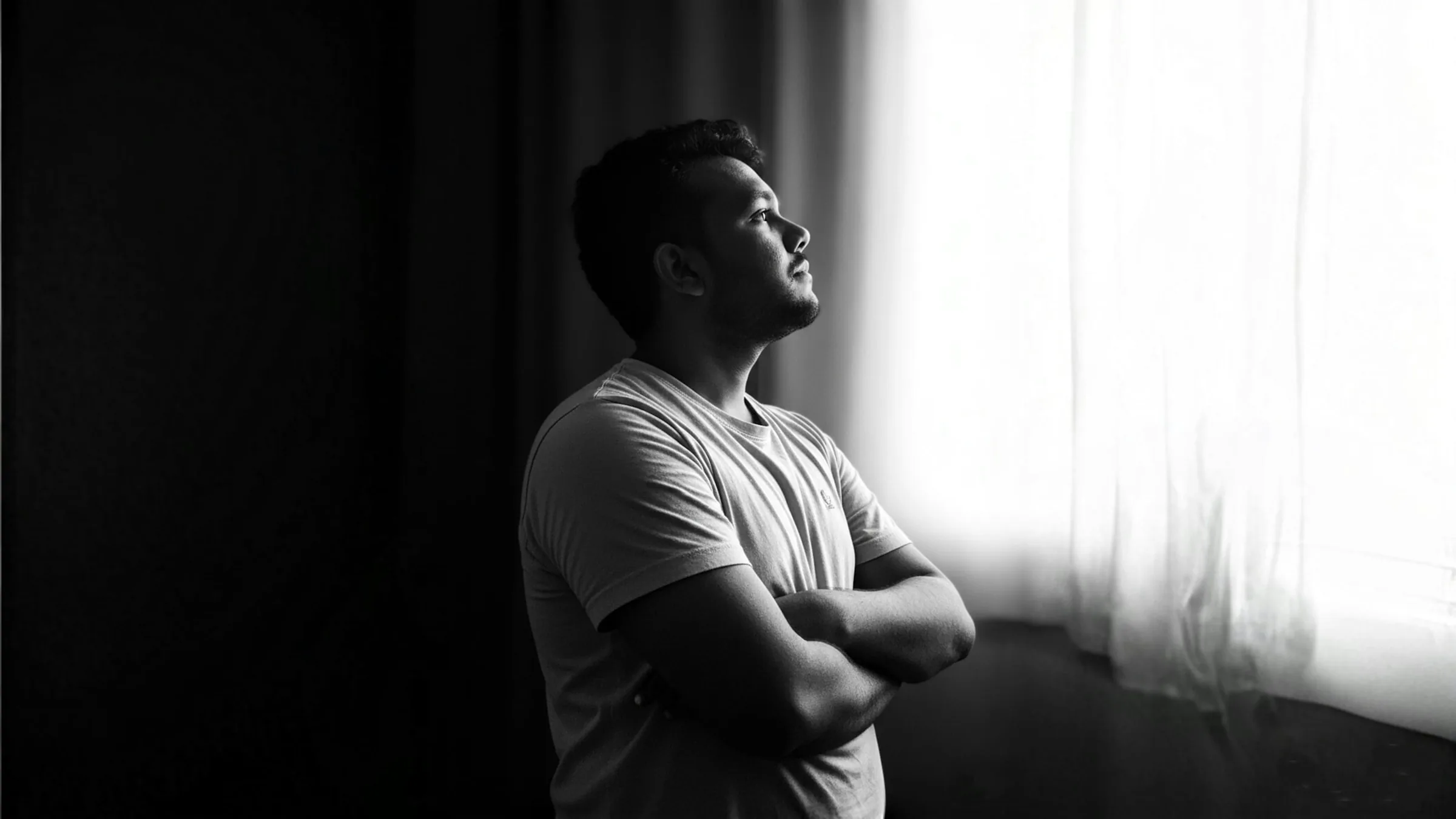 Father standing quietly by a window, grief counseling for fathers and partners after pregnancy loss in Charlotte, NC